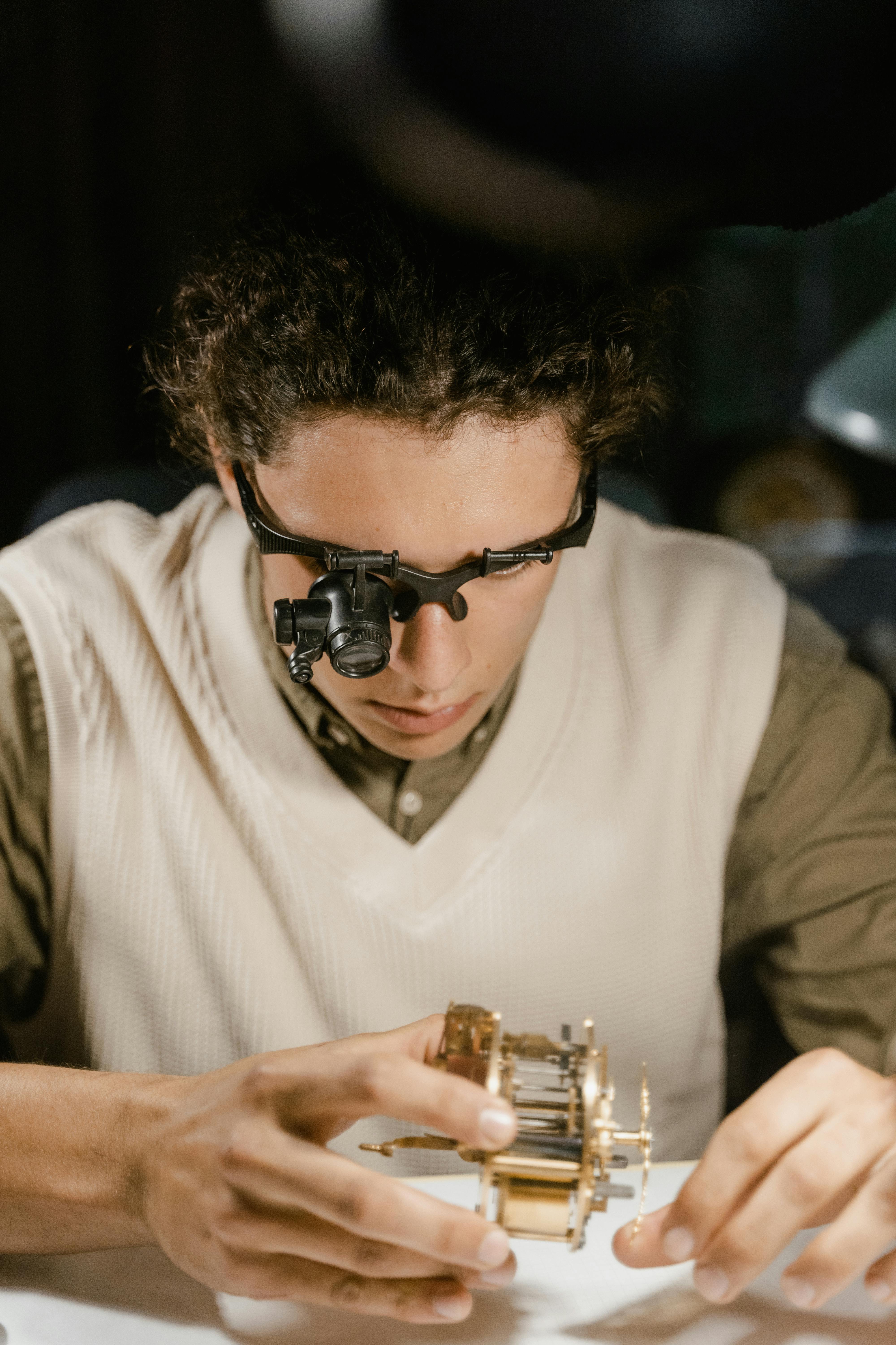 Young watchmaker wearing a loupe headset while working on a precision mechanism
